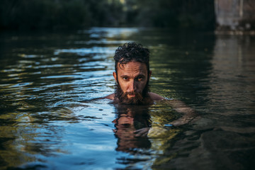 Man with beard on the river swimming