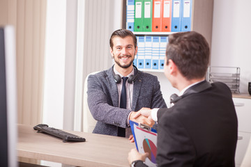 Business partners shaking hands in the office. Two businessman in formal suits shaking hands in corporate office eviroment