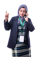 A beautiful, confident Muslim woman with a happy expression  wearing hijab, suit and wearing a blank ID tag or name card on a lanyard  making call with her cell phone isolated on white background.