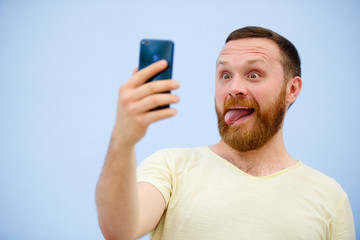 man makes faces in a funny and humorous phone shows a language, an advertising company
