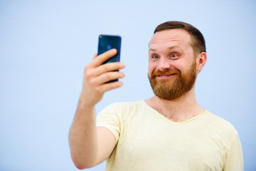 man makes faces in a funny and humorous phone shows a language, an advertising company