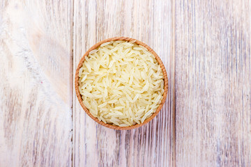 Rice in a bowl. Bowl with rice on a wooden oak background, cutting board, top view.