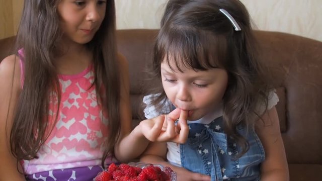 A child eats raspberries. Little girls eat raspberries.