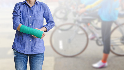 Female patient wearing blue shirt with green cast on arm isolated on blurred background woman riding a bicycle, body injury concept