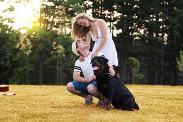 Young couple in love with dog rottweiler in the nature