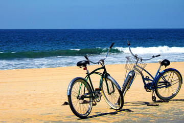 Two Bicycles, parked on a beach near the ocean