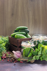 Conservation of cucumbers.Products prepared for marinating:cucumbers in wooden box and in the  glass jars,herbs,spices,garlic