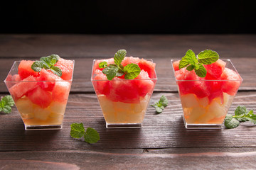 Delicious fruits salad with watermelon, melon,strawberry and  fresh mint  in portionned  bowls  on the wooden table