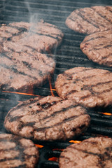 hamburgers and hot dogs cooking on grill with flames