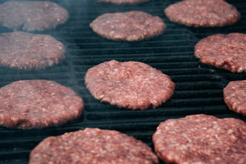 hamburgers and hot dogs cooking on grill with flames