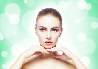 Naklejka premium Portrait of young, beautiful and healthy woman: over teal background. Healthcare, spa, makeup and face lifting concept.