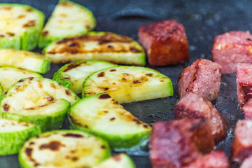 cooking slices of sausage and vegetables on the grill, background with a bokeh effect