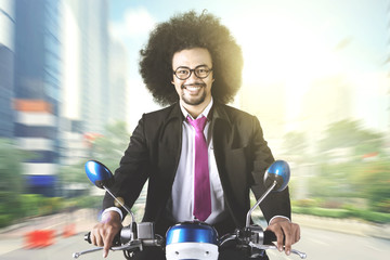 Afro businessman rides motorcycle in the city