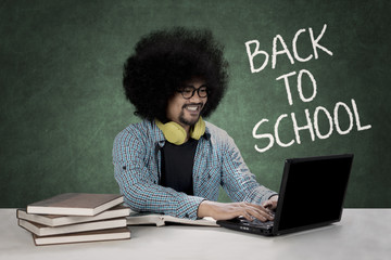 Afro student typing on a laptop