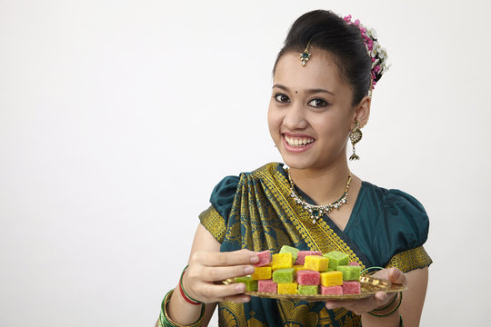 indian woman holding tray of candy