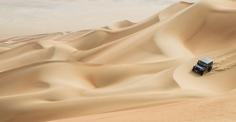 car driving in Rub al Khali Desert at the Empty Quarter, in Abu Dhabi, UAE