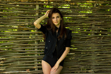 tender beautiful brunette in black suit stands near a wooden wall