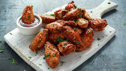 Baked chicken wings with sesame seeds and sweet chili sauce on white wooden board. © grinchh
