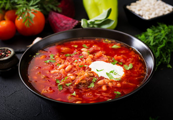 Traditional Ukrainian Russian borscht with white beans on the black bowl