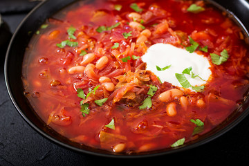 Traditional Ukrainian Russian borscht with white beans on the black bowl