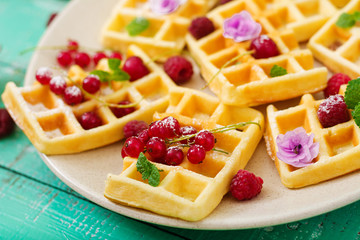 Belgium waffles with raspberries and yogurt on plate.