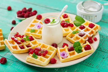 Belgium waffles with raspberries and yogurt on plate.