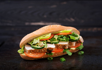Big sandwich with chicken breasts, tomato, cucumber and herbs.