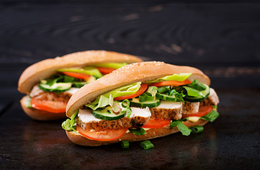 Big sandwich with chicken breasts, tomato, cucumber and herbs.