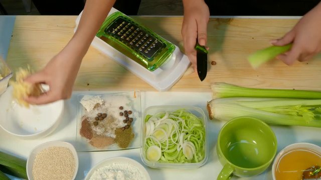 Woman's hands chop the celery and shift the cheese into a plate