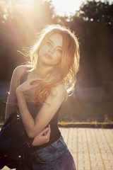 Fototapeta na wymiar Beautiful young model with lush wave hair posing in rays of sun