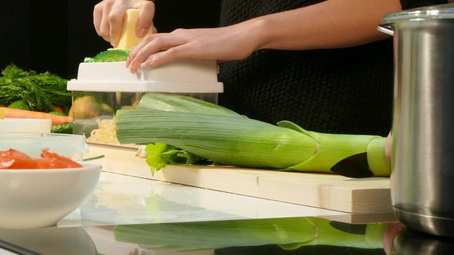Woman's hands cut the leeks and chop the cheese