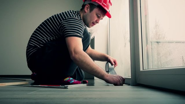 Professional carpenter guy taping down flooring underlay with tape
