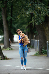 Fototapeta premium Beautiful young woman enjoying in walk with her little red poodle puppy. 