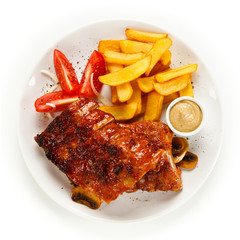 Grilled ribs, French fries and vegetables on white background 