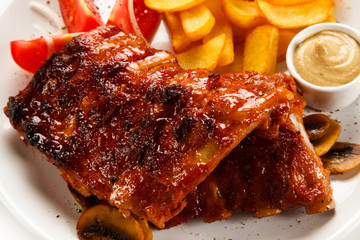 Grilled ribs, French fries and vegetables on white background 