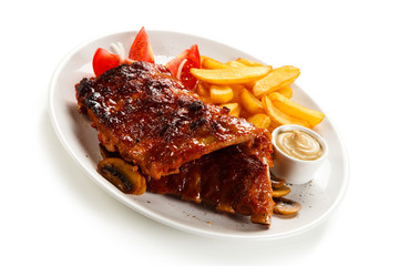 Grilled ribs, French fries and vegetables on white background 