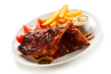 Grilled ribs, French fries and vegetables on white background 