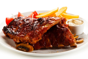 Grilled ribs, French fries and vegetables on white background 