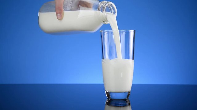 Cold milk bottle pouring into Clear glass