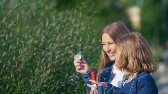 Mom and daughter with soap bubbles outdoors