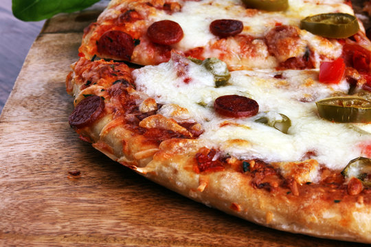 Hot pizza slice with melting cheese on a rustic wooden table. Italien food concept