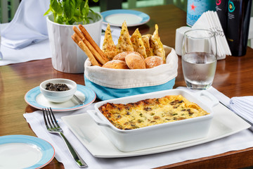 Fresh lasagna in a baking dish with bread basket.