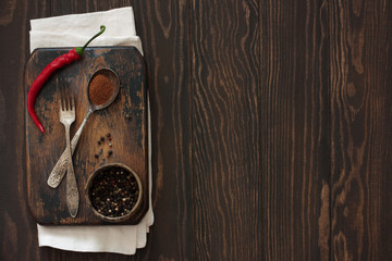 Old cutting board, peppers and vintage fok and spoon on a natural wood background