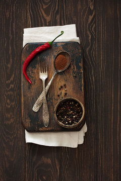 Old cutting board, peppers and vintage fok and spoon on a natural wood background