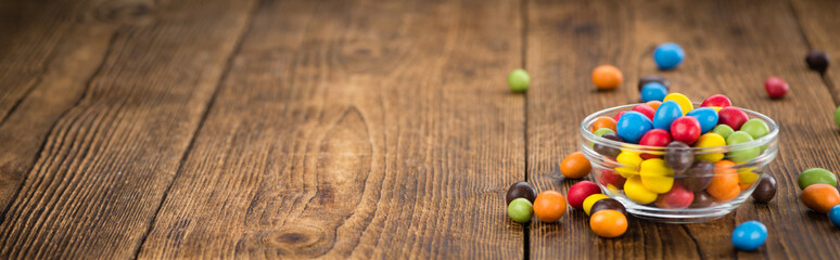 Portion of Cocolate coated Peanuts on wooden background (selective focus)