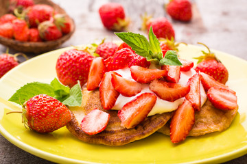 Fritters with yogurt, sliced strawberries and mint leaves on a plate