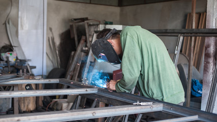 Industrial welder working a welding metal with protective mask