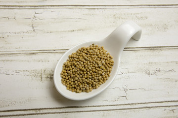 Yellow mustard seeds in white china spoon.