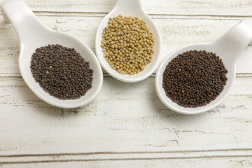 Whole mustard seeds in white china spoons