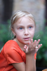 Thoughtful face of a cute blond girl at a cafe table